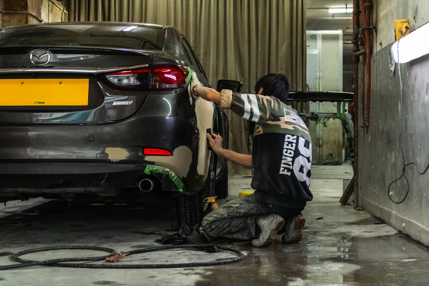 Carrossier préparant l'arrière d'une voiture avant peinture